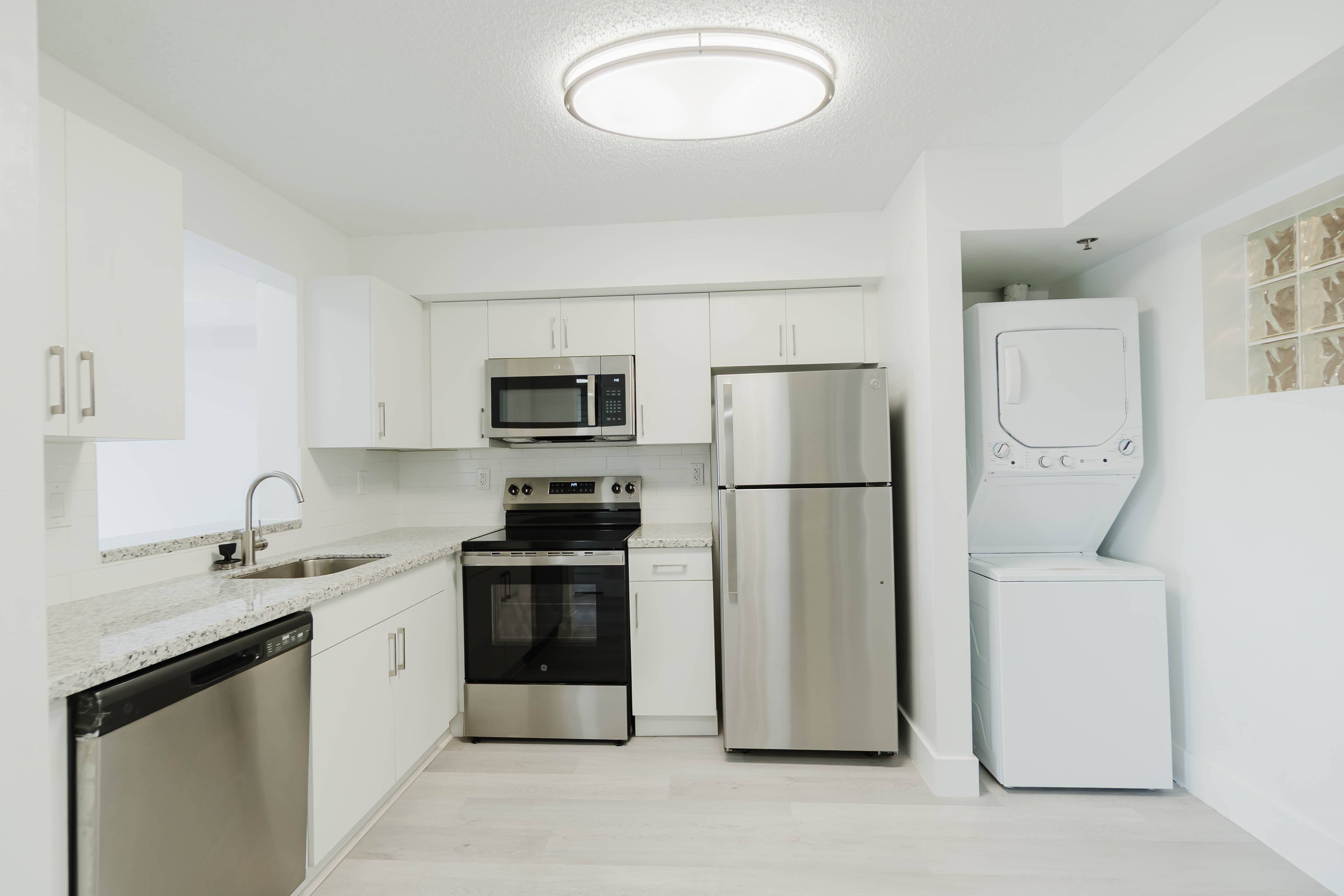 A modern kitchen with stainless steel appliances and white cabinetry.